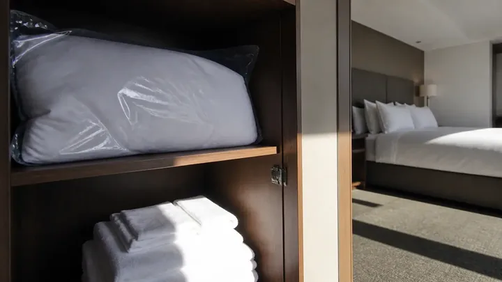 Shelf with a wrapped pillow and folded towels beside a mirror