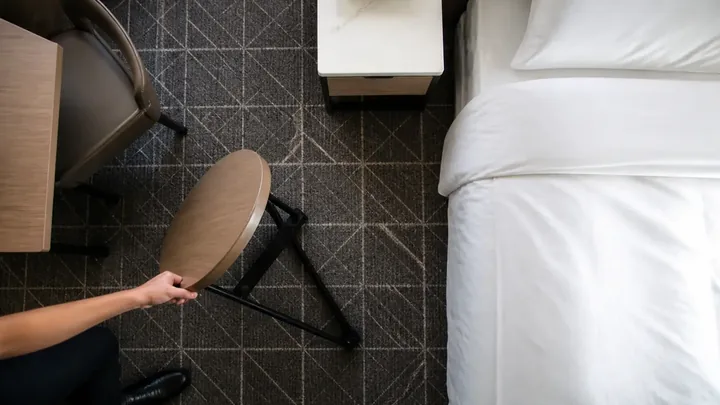 Overhead view of a hand tipping over a round side table